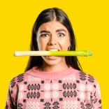 A girl holding a leek in her mouth