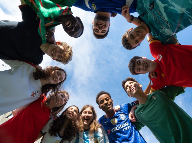 A group of children in a circle looking down at the camera.