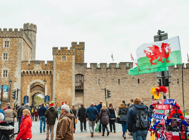 A crowd of rugby fans outside a historic castle in the middle of a busy town centre