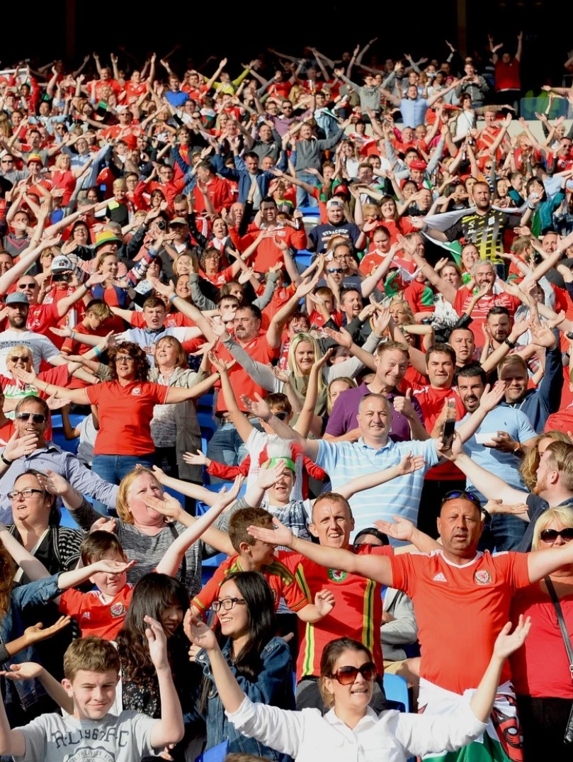 A crowd of people at a football game singing the national anthem.