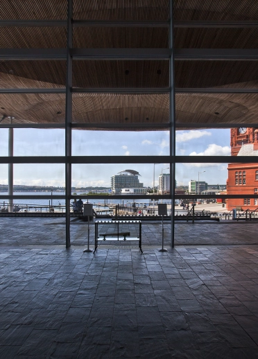 inside of building with stone floor and view through window to bay beyond.