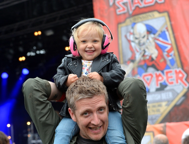 Gŵr gyda dyn ifanc ar ei ysgwyddau mewn gŵyl.