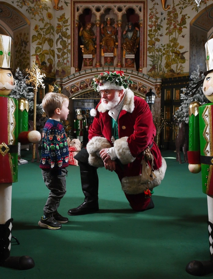 Siôn Corn kneeling down and talking to a child.