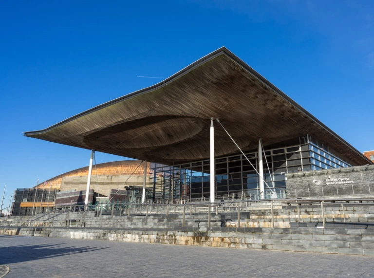 An external shot of a grand slate and glass fronted building with a large wooden roof