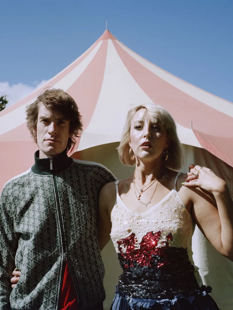 Zwei Menschen stehen vor einem Zelt.