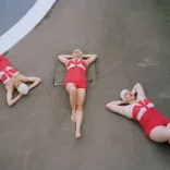 Three people lying on the ground with their hands behind their backs.