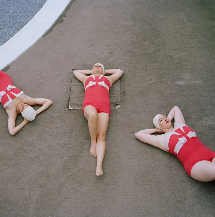 Drei Personen, die mit den Händen auf dem Rücken auf dem Boden liegen.