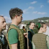 Four performers dressed in traditional Welsh garments standing outside against a blue sky