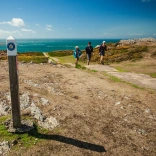 Walkers on the Wales Coast Path with the sea in the background.