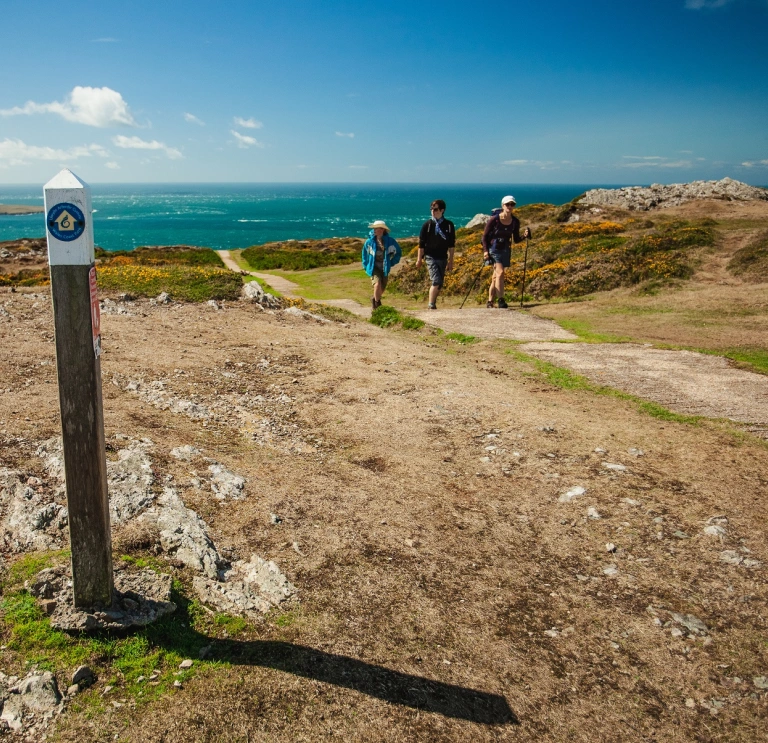 Walkers on the Wales Coast Path with the sea in the background.