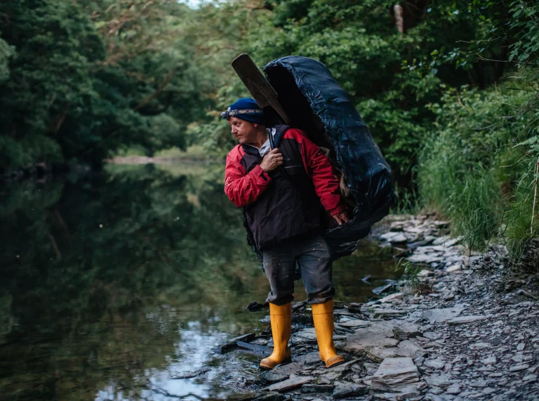 Un homme portant un coracle, debout sur les berges de la rivière