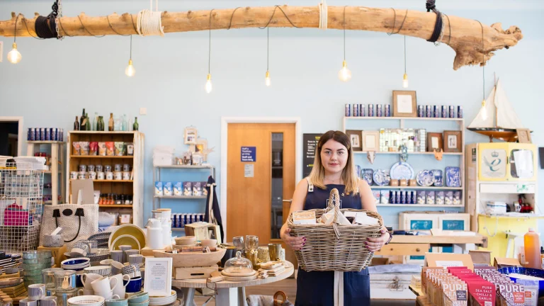 Eine Frau in einem Laden, die einen Korb mit Produkten im Arm hält.