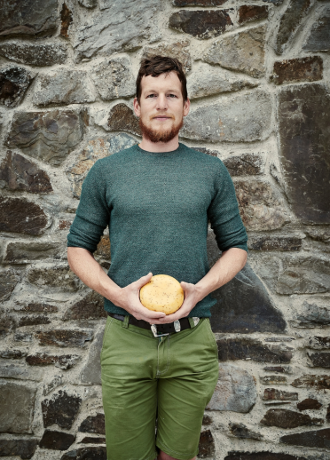 A man standing in front of a door holding a cheese round 