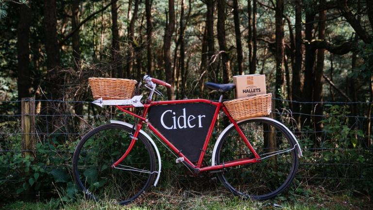 Una bicicleta roja con sidra escrito y sidra Hallets en las cestas de mimbre.