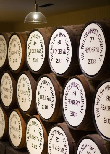 Des barriques de whisky Penderyn empilés. Chaque barrique porte la marque «  Penderyn » . The Welsh Whisky Company