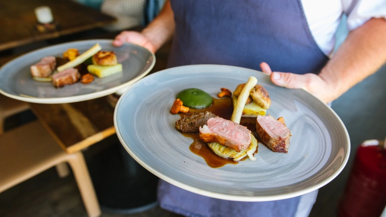 Un chef que lleva dos platos de comida.