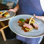 Ein Koch, der zwei Teller mit Essen trägt.