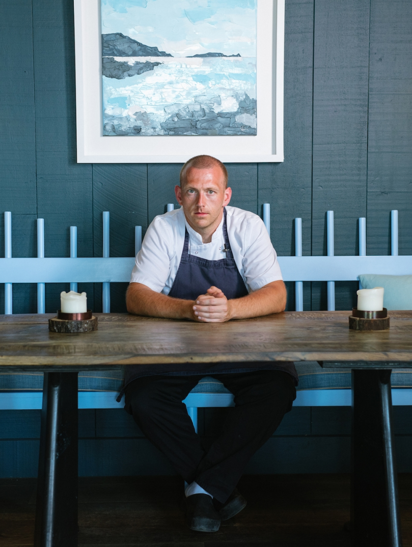 Hywel Griffith sentado en una mesa en su restaurante Beach House.