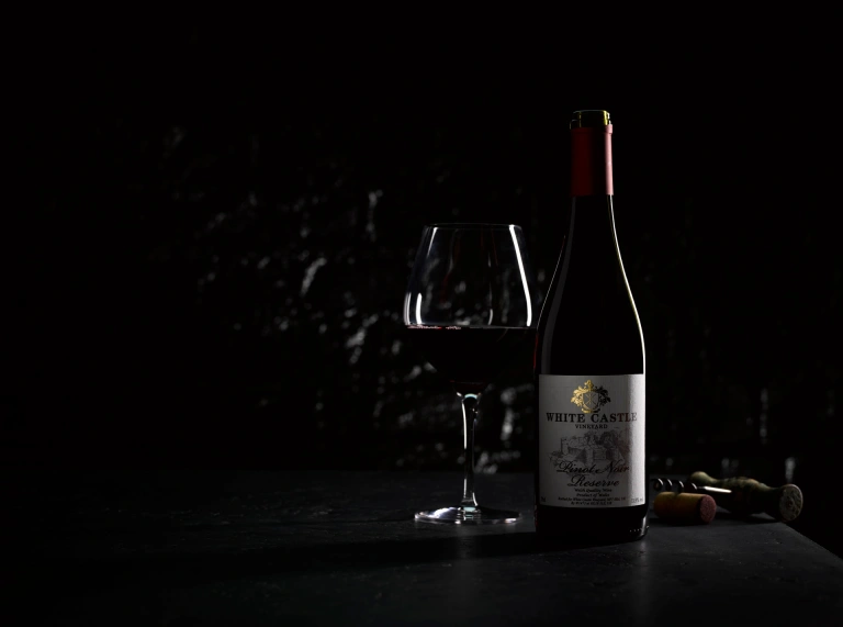 Una copa y una botella de vino tinto.