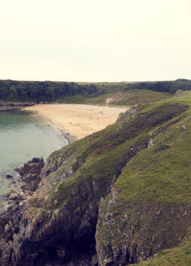 A beautiful sandy cove surrounded by blue sea and green cliffs